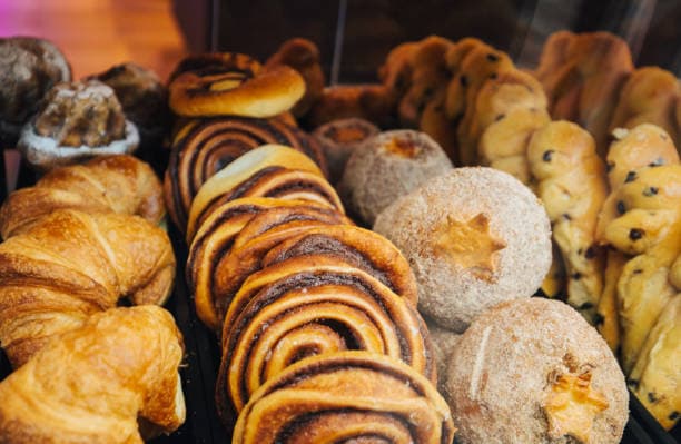 A variety of baked goods including croissants, cinnamon rolls, and sweet pastries displayed in a pastry case. A variety of baked goods including croissants, cinnamon rolls, and sweet pastries displayed in a pastry case.