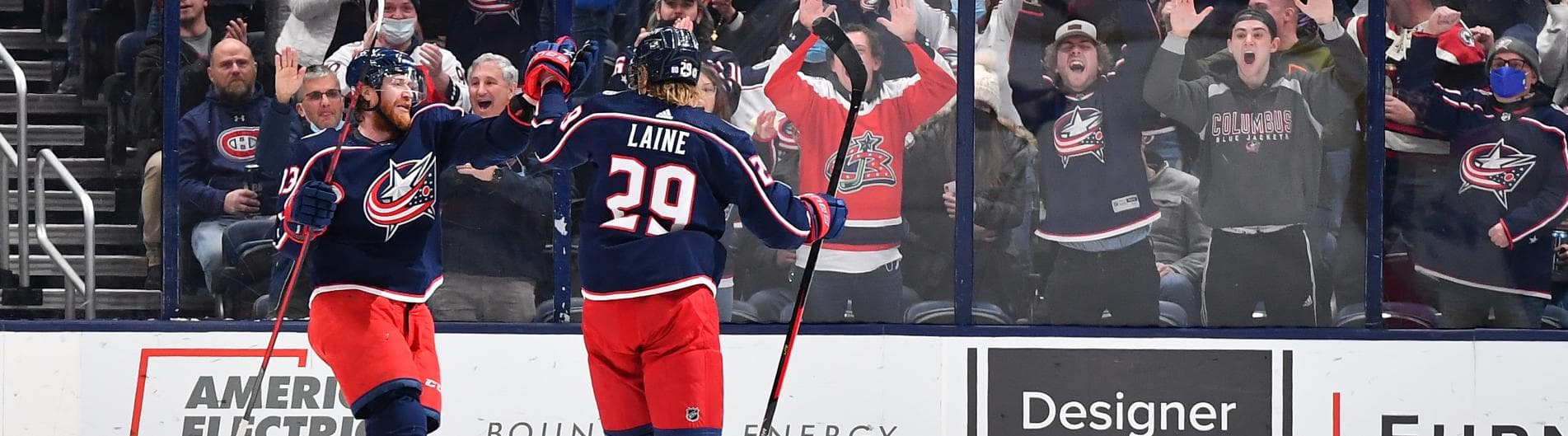 Columbus Blue Jackets players celebrate a goal as excited fans cheer in the background. Columbus Blue Jackets players celebrate a goal as excited fans cheer in the background.