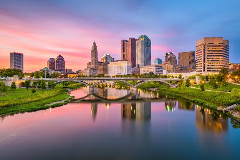 City skyline at sunset reflected in a river.