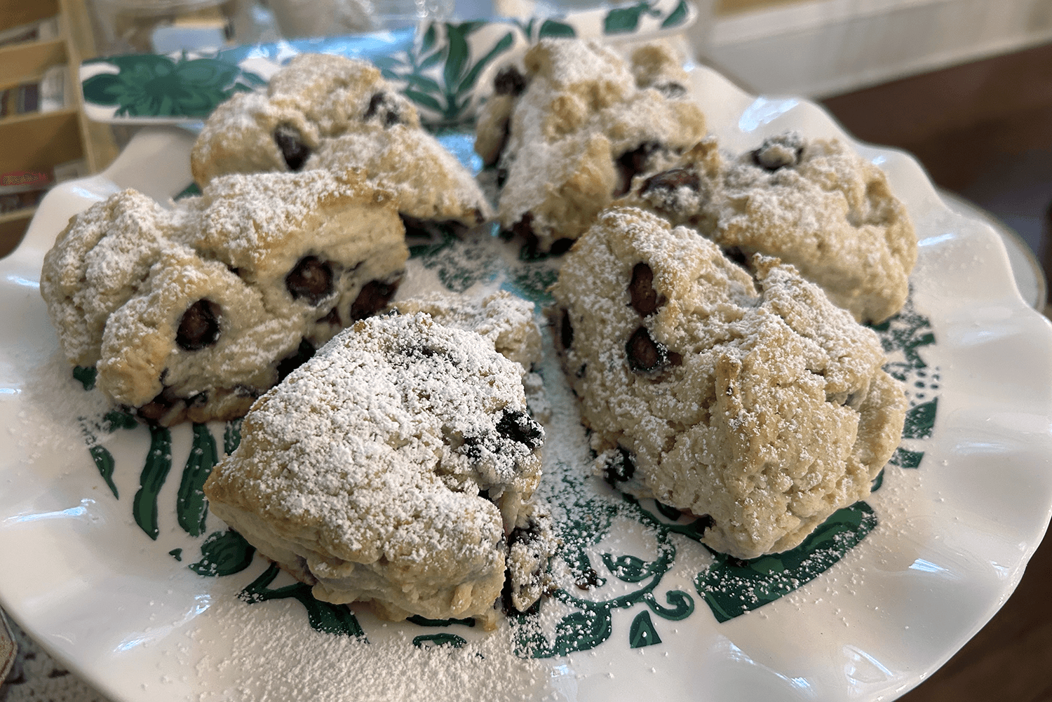 A plate of freshly baked scones dusted with powdered sugar and studded with berries.